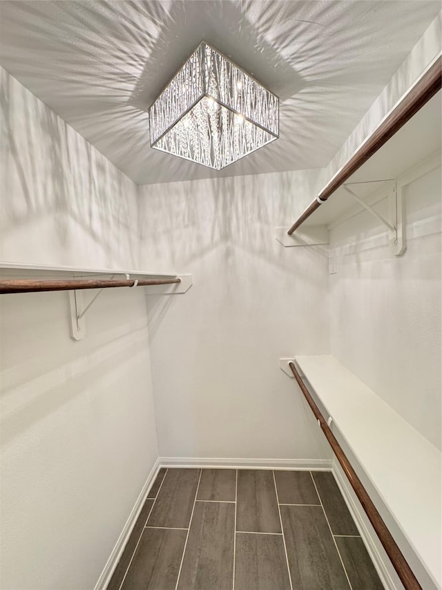 spacious closet with an inviting chandelier and wood finish floors