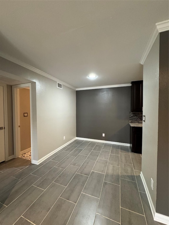 below grade area with visible vents, baseboards, and ornamental molding