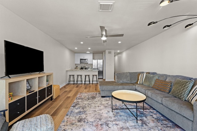 living room with visible vents, baseboards, ceiling fan, recessed lighting, and light wood-style flooring