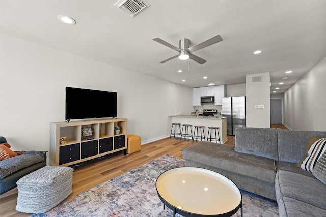 living room with light wood finished floors, visible vents, recessed lighting, and ceiling fan