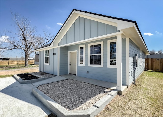 view of front of house with a patio, board and batten siding, and fence