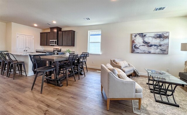 dining area featuring visible vents, light wood-style flooring, and baseboards