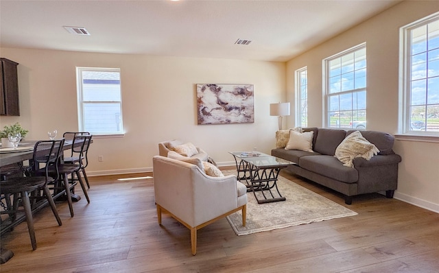 living room with wood finished floors, visible vents, and baseboards