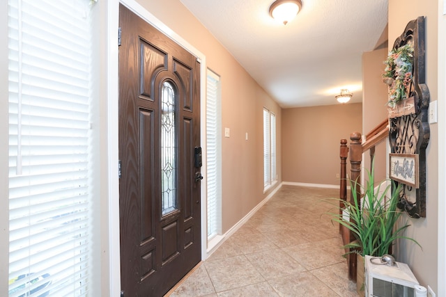 entryway with light tile patterned floors, baseboards, and stairs