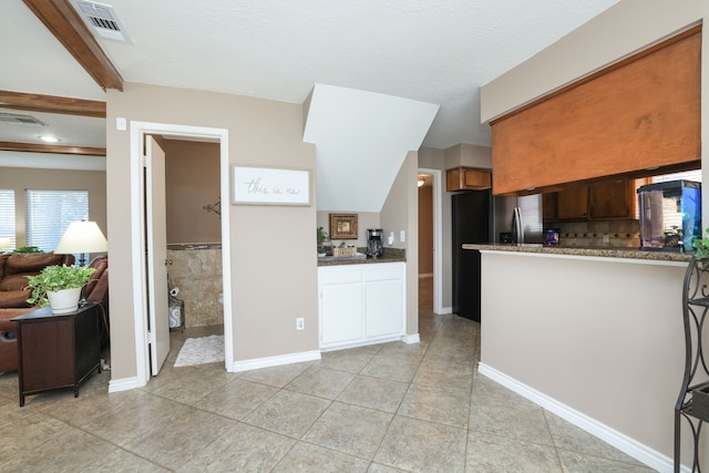 kitchen featuring visible vents, baseboards, a peninsula, and light tile patterned flooring