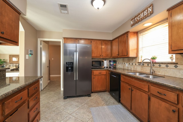 kitchen featuring tasteful backsplash, visible vents, appliances with stainless steel finishes, brown cabinetry, and a sink