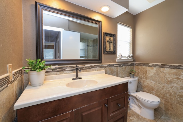 full bathroom featuring toilet, tile walls, wainscoting, and vanity