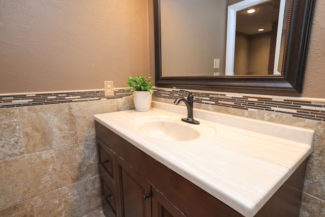 bathroom featuring a wainscoted wall, vanity, and tile walls