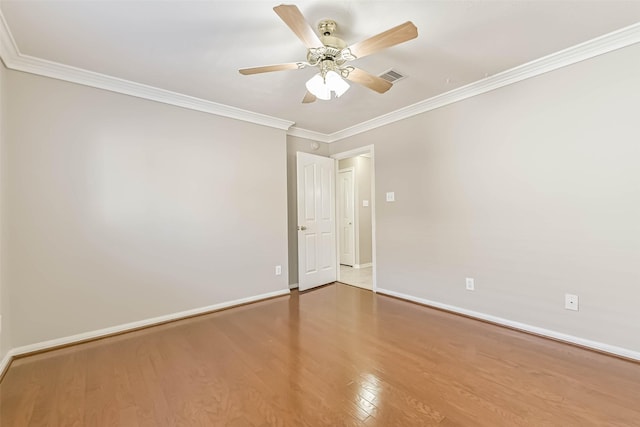 spare room with ornamental molding, wood finished floors, visible vents, and baseboards