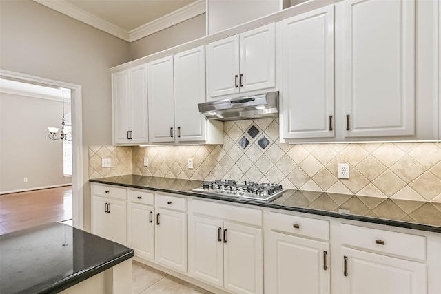 kitchen featuring decorative backsplash, stainless steel gas stovetop, crown molding, under cabinet range hood, and dark countertops