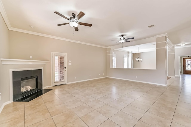 unfurnished living room with a tiled fireplace, plenty of natural light, ceiling fan with notable chandelier, and crown molding