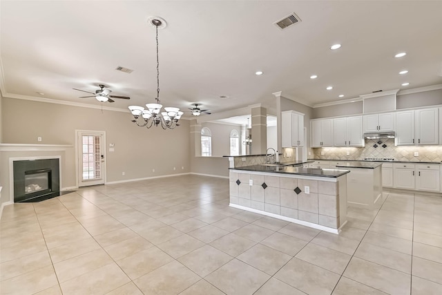 kitchen with visible vents, under cabinet range hood, backsplash, open floor plan, and light tile patterned floors