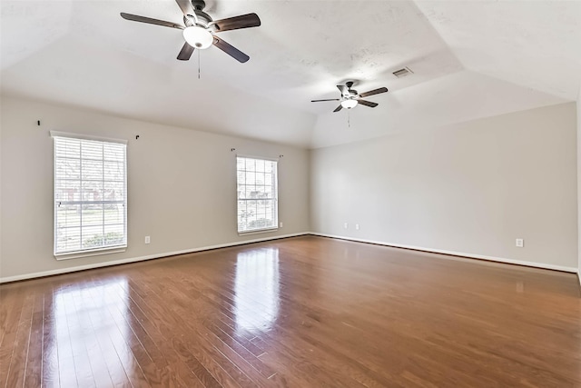 unfurnished room featuring visible vents, ceiling fan, baseboards, vaulted ceiling, and wood finished floors