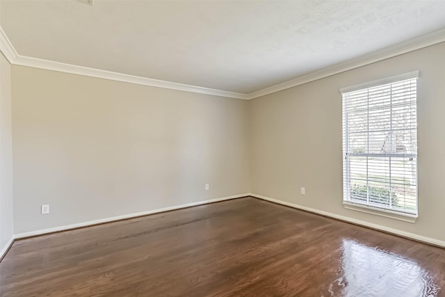 empty room with dark wood-type flooring, baseboards, and ornamental molding