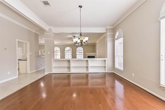 unfurnished dining area with visible vents, wood finished floors, an inviting chandelier, and ornamental molding