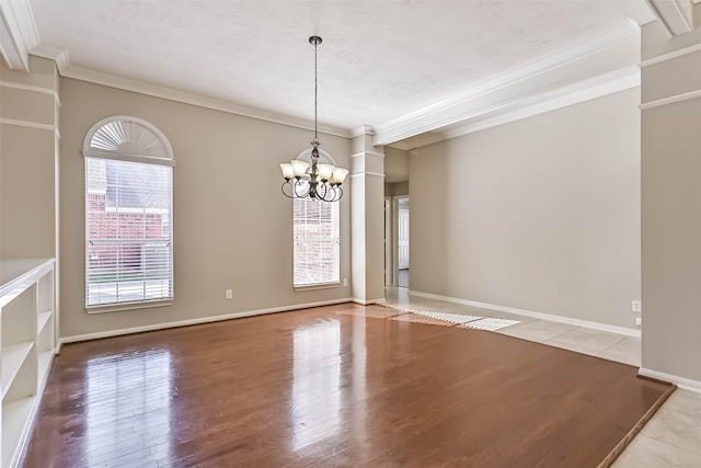 spare room with baseboards, a notable chandelier, wood finished floors, and crown molding