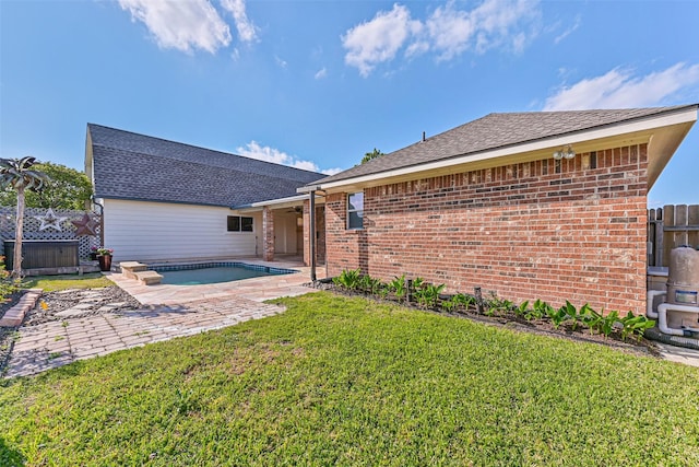 back of property with a ceiling fan, brick siding, a lawn, and a patio area