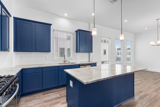 kitchen with blue cabinetry, stainless steel appliances, light wood-type flooring, and a sink