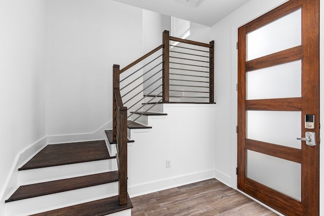 stairway with wood finished floors and baseboards