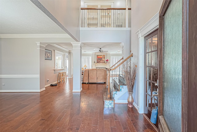 foyer entrance with hardwood / wood-style flooring, crown molding, decorative columns, ceiling fan, and stairs