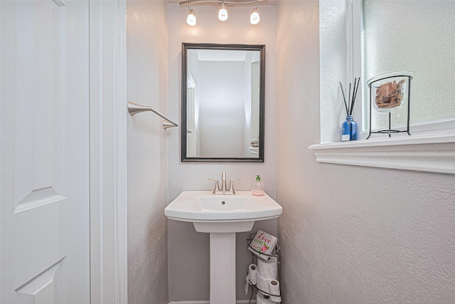 bathroom featuring a textured wall and a sink