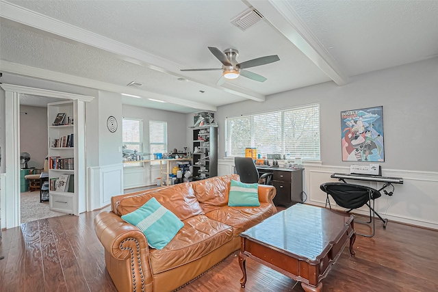 living area featuring wood finished floors, visible vents, ceiling fan, a textured ceiling, and beamed ceiling