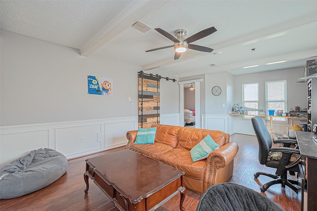 living room with visible vents, beam ceiling, a ceiling fan, a textured ceiling, and wood finished floors