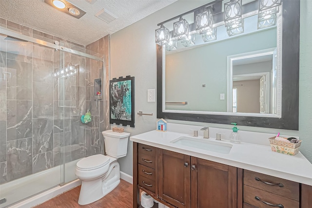 full bath featuring toilet, a stall shower, wood finished floors, a textured ceiling, and vanity