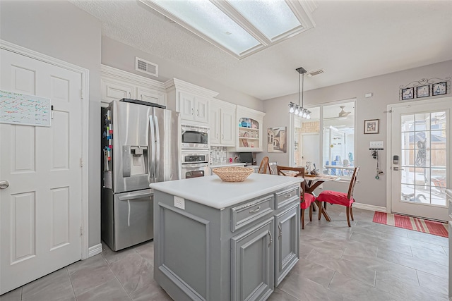 kitchen featuring visible vents, gray cabinetry, stainless steel appliances, and light countertops