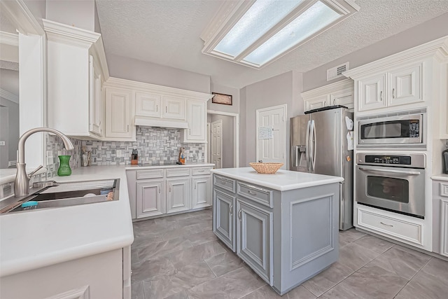 kitchen featuring visible vents, light countertops, gray cabinets, stainless steel appliances, and a sink