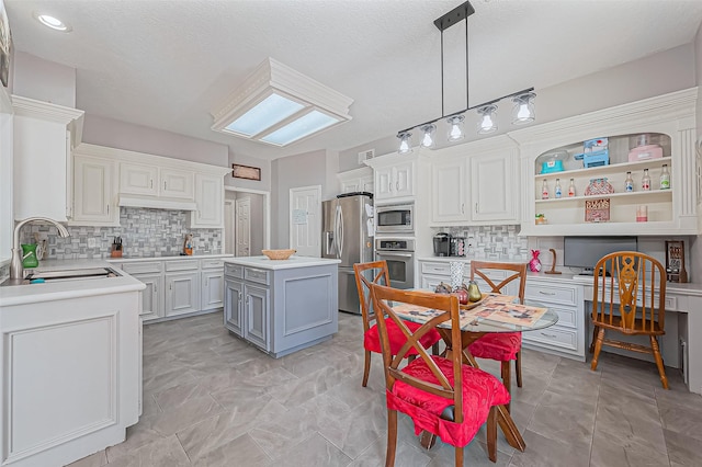 kitchen featuring gray cabinetry, a sink, a kitchen island, appliances with stainless steel finishes, and light countertops