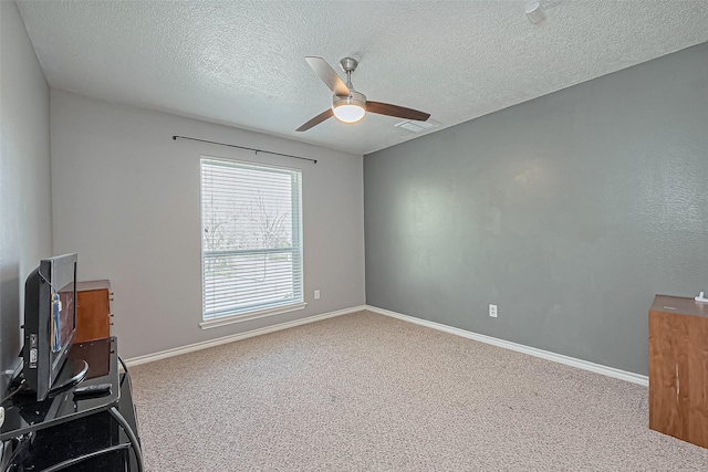 carpeted empty room featuring visible vents, a textured ceiling, baseboards, and a ceiling fan