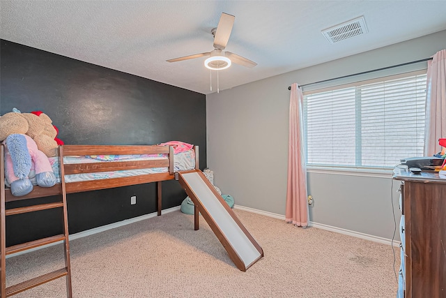 carpeted bedroom featuring visible vents, baseboards, a textured ceiling, and ceiling fan