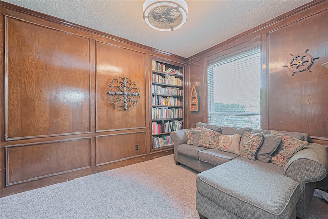 carpeted living area with built in features, wood walls, and a textured ceiling