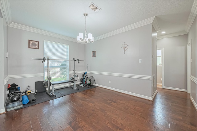 workout room with hardwood / wood-style floors, baseboards, visible vents, ornamental molding, and a notable chandelier