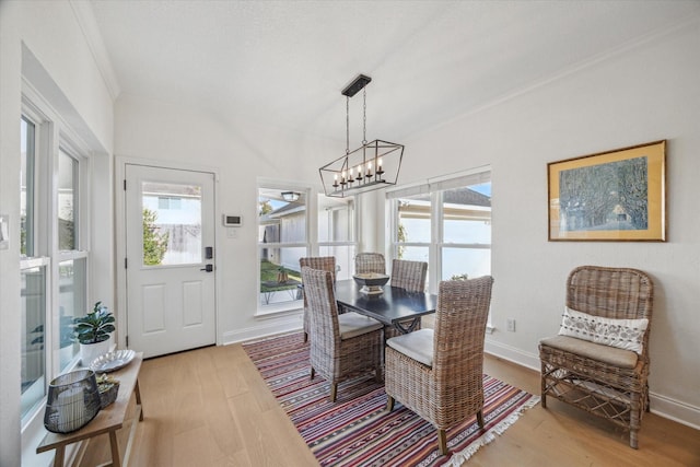 dining area with light wood-type flooring, baseboards, a chandelier, and crown molding