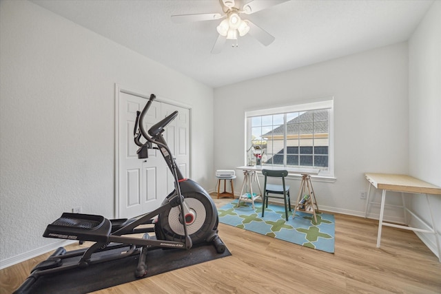 workout room with baseboards, wood finished floors, and a ceiling fan