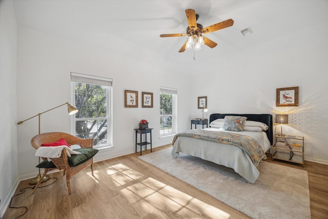 bedroom with a ceiling fan, wood finished floors, visible vents, and baseboards