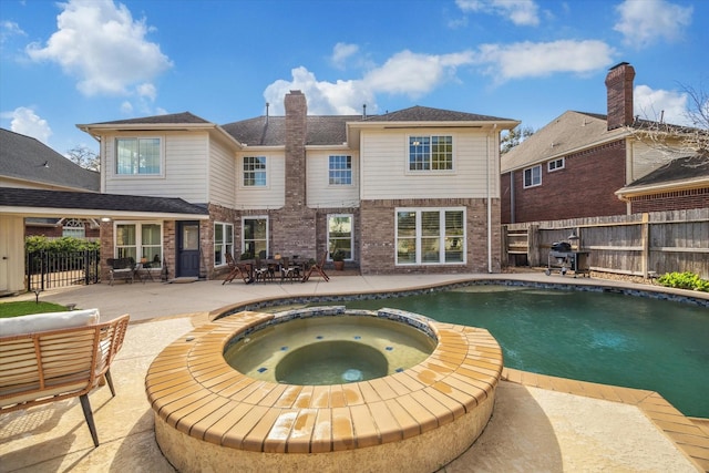 view of pool with grilling area, fence, a pool with connected hot tub, and a patio area