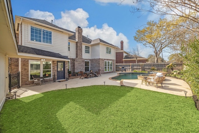 rear view of house featuring a patio area, brick siding, a fenced backyard, and a lawn