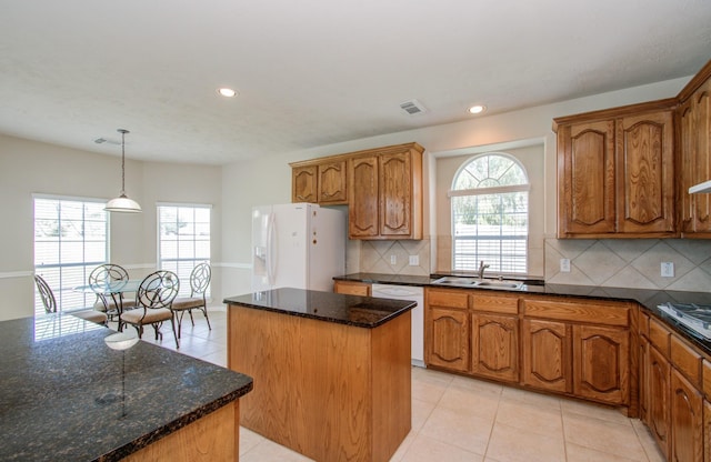 kitchen with white appliances, brown cabinetry, a kitchen island, and a sink