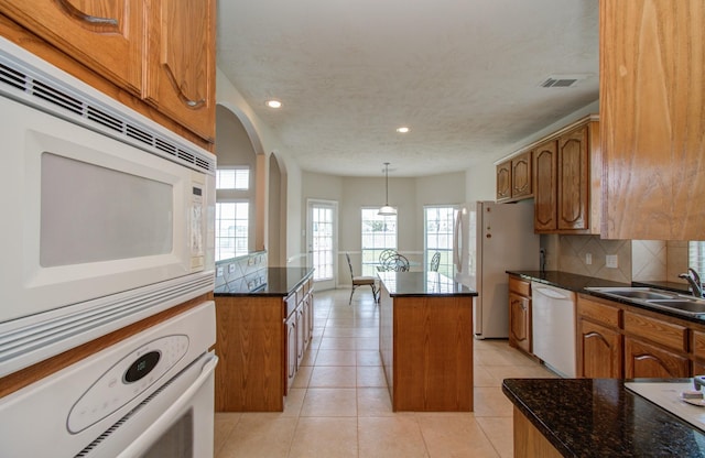 kitchen featuring white appliances, brown cabinetry, visible vents, and a sink