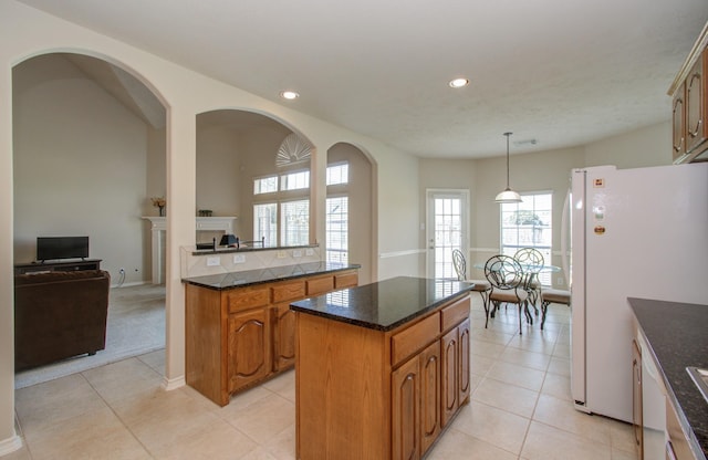 kitchen with brown cabinets, a kitchen island, freestanding refrigerator, recessed lighting, and light tile patterned floors