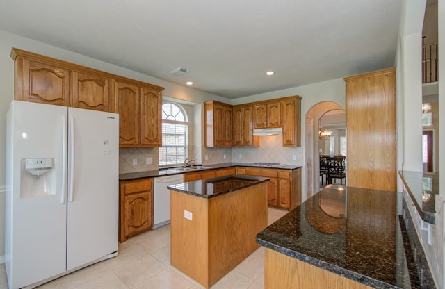 kitchen with visible vents, under cabinet range hood, a sink, white appliances, and arched walkways