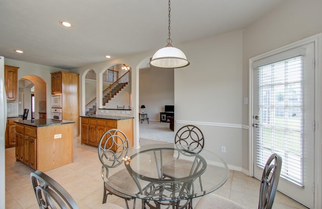 dining room featuring arched walkways, recessed lighting, a healthy amount of sunlight, and stairs