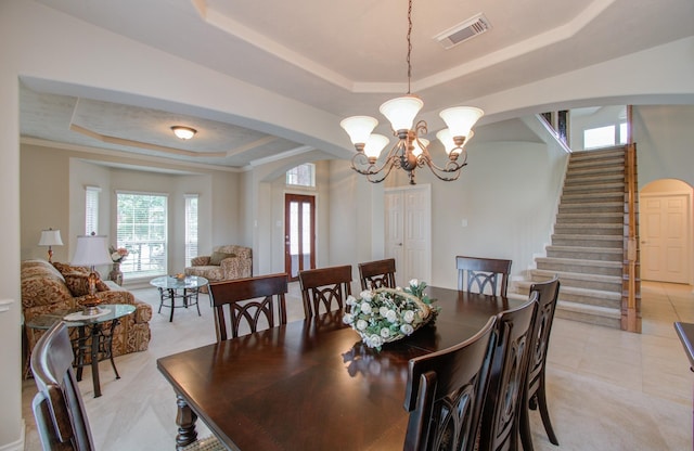 dining area featuring visible vents, stairs, a tray ceiling, an inviting chandelier, and arched walkways