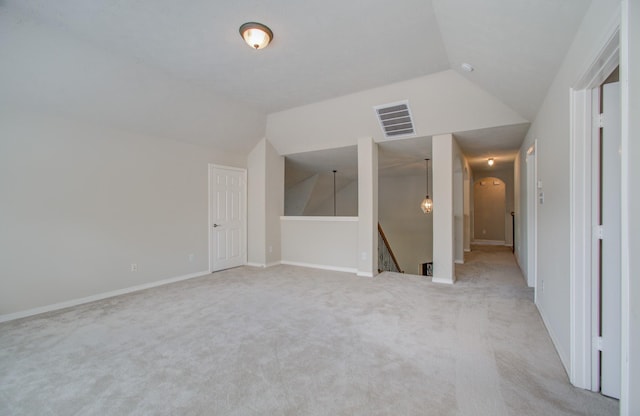 interior space featuring visible vents, baseboards, lofted ceiling, arched walkways, and light colored carpet