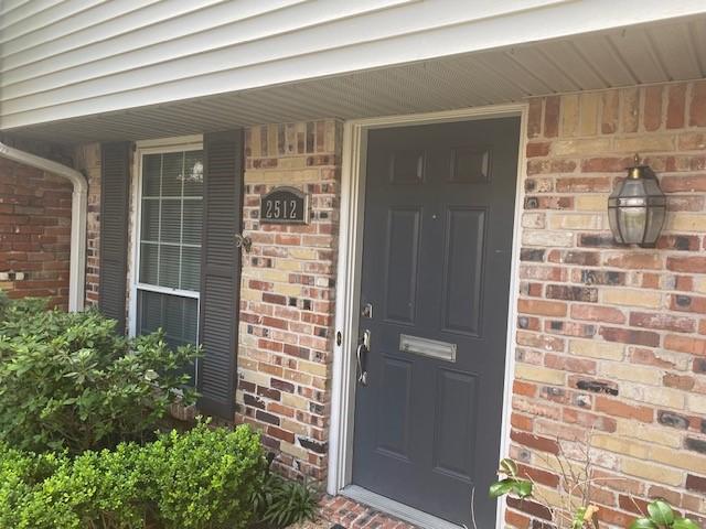 view of exterior entry with covered porch and brick siding