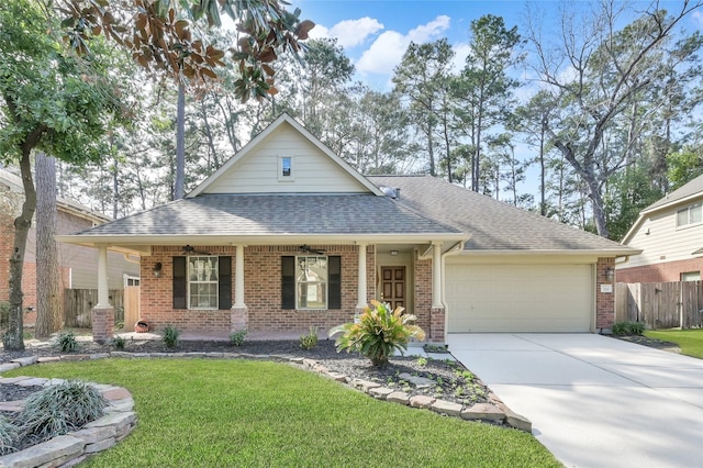 view of front of property featuring brick siding, fence, a front yard, roof with shingles, and an attached garage