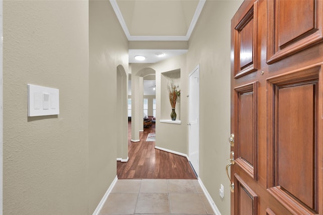 hall featuring light tile patterned floors, arched walkways, and baseboards